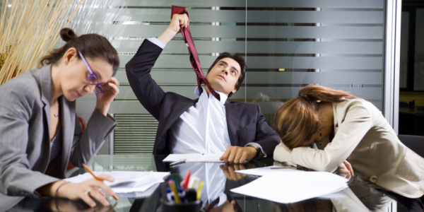 Three people in a conference room having a meeting, all hating life